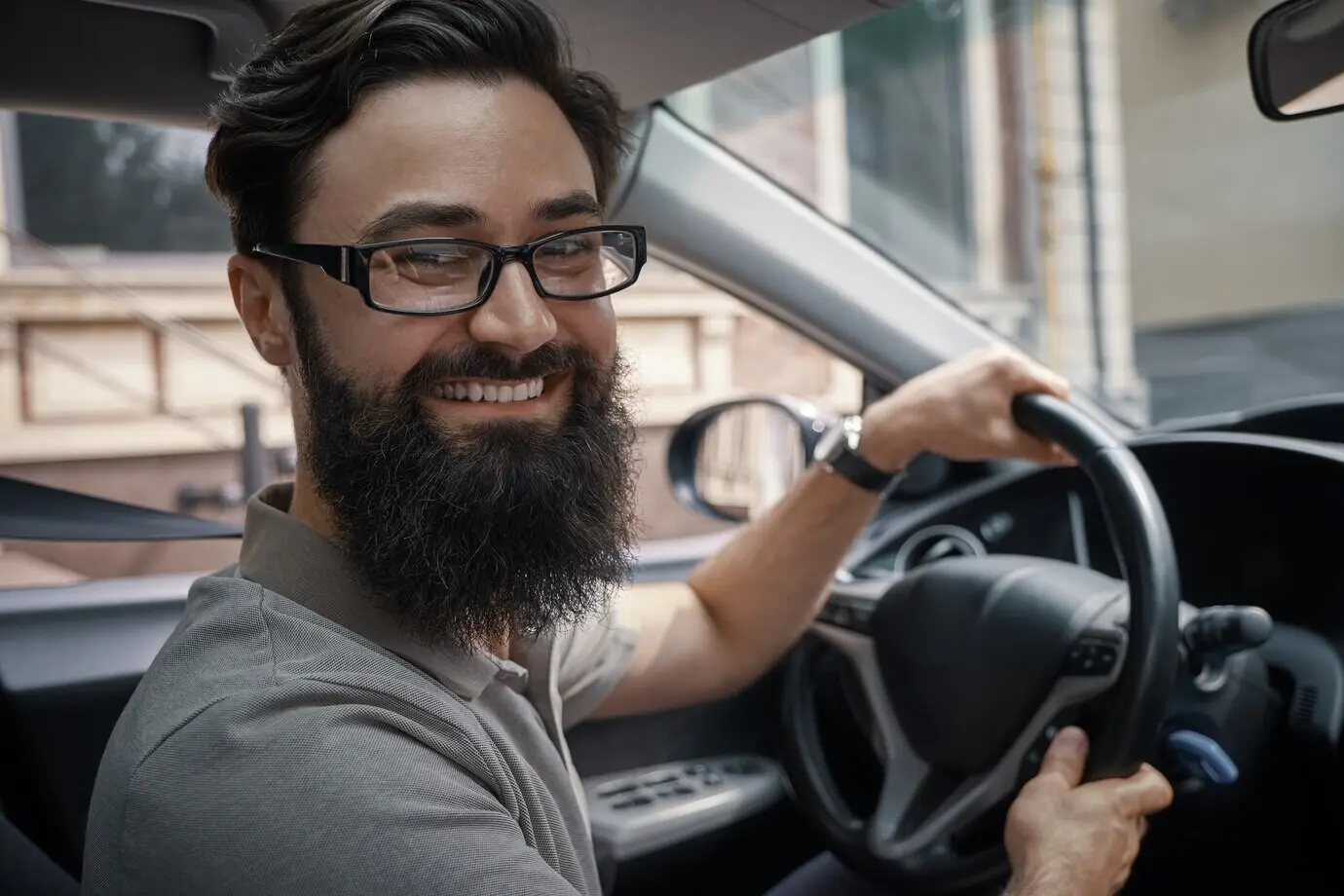 A happy, handsome man is driving the car.