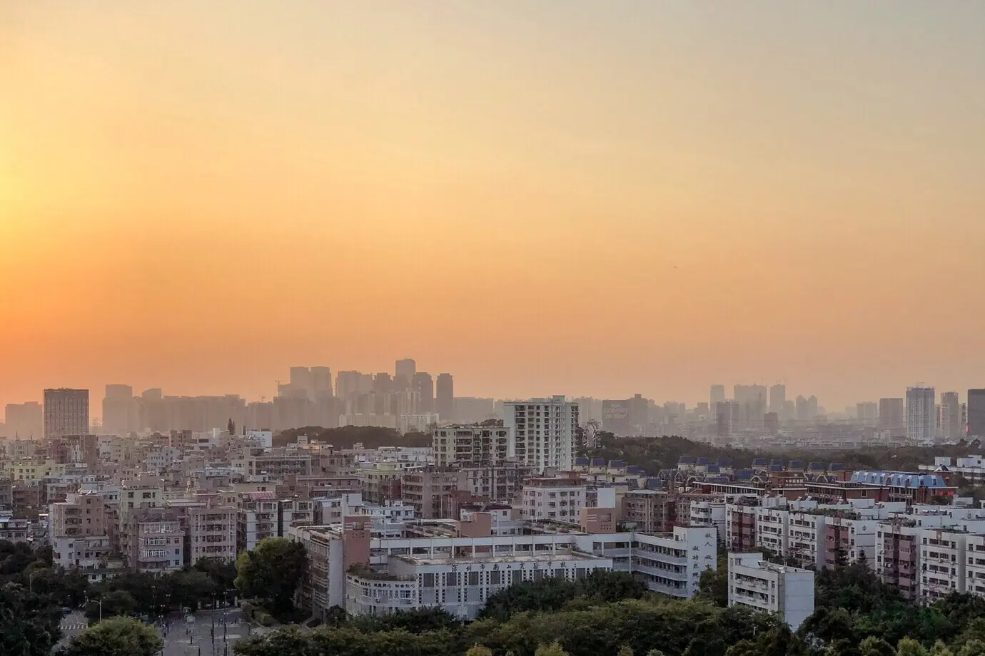 A beautiful panorama of city buildings under an orange sky at sunset.